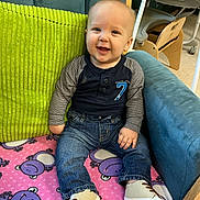 Giovanni joined the competition — help win amazing prizes! baby, child, smiling, blue_armchair, green_cushion, pink_blanket, hippo_pattern, denim_jeans, shirt, shoes, indoor, flooring, wooden_chair, high_chair, cute, happy, seated, portrait, person, casual_clothing