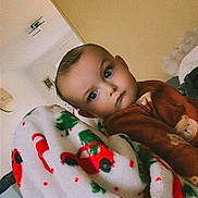 Lyzio participe au concours pour gagner de l'argent avec cette photo : blanket, blue_eyes, brown_clothing, child, cozy, curious, cute, expression, face, framed_photo, furniture, home, indoor, living_room, plaid, portrait, soft_texture, toddler, wall_clock, young_child