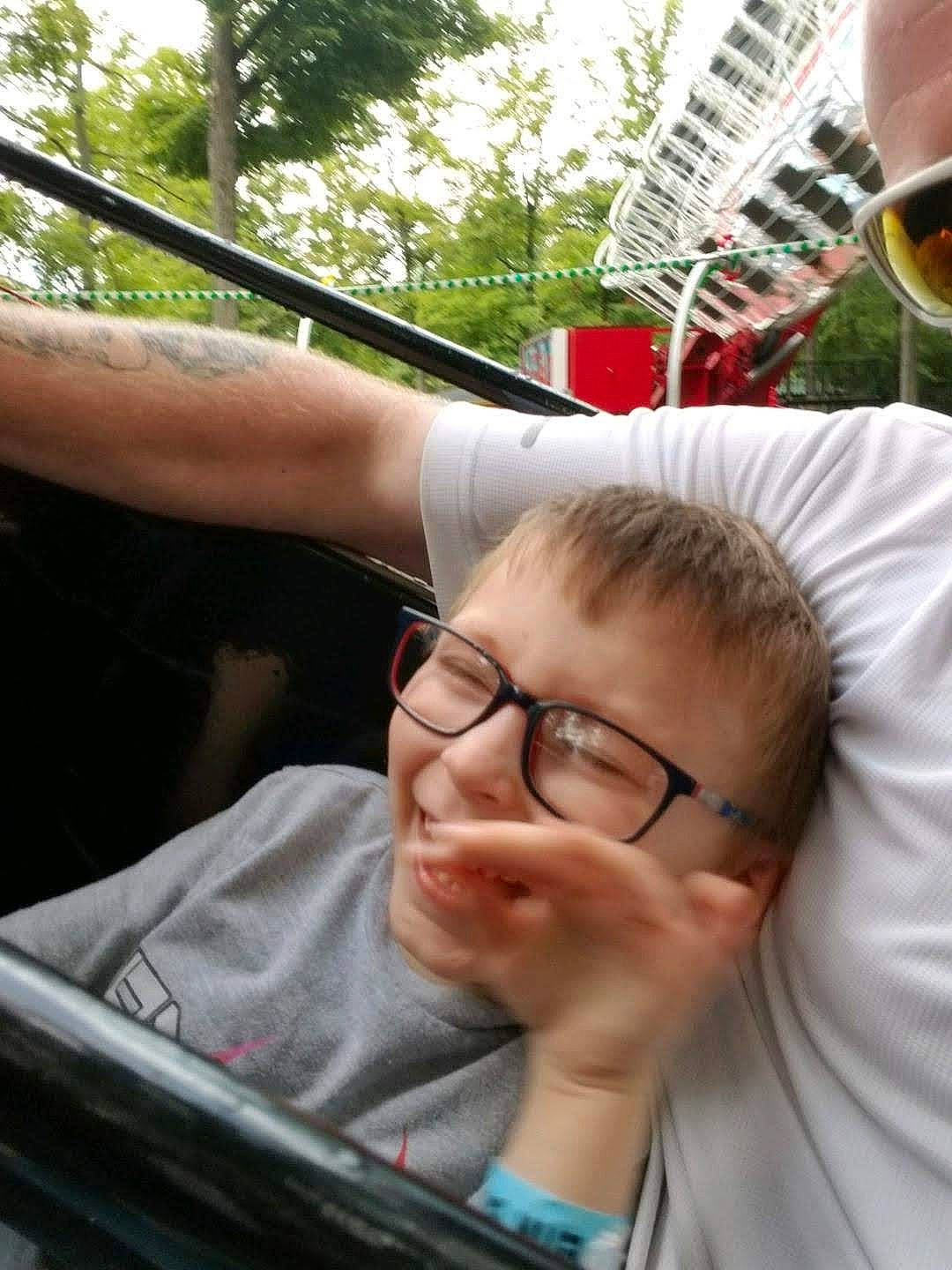 Zackary is registered to the contest to win money with this photo: auto_part, automotive_design, automotive_exterior, automotive_window_part, cool, eyewear, fashion_accessory, fun, gesture, glass, glasses, leisure, person, recreation, sitting, t_shirt, tableware, tree, vehicle_door, vision_care