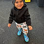 George is registered to the contest to win money with this photo: child, toddler, smiling, beanie, hoodie, pants, boots, toy, pavement, outdoor, playground, colorful, walking, cute, happy, person, young_child, casual_clothing, play, daylight