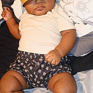 Mileyah is registered to the contest to win money with this photo: baby, infant, crown, burger_king, paper_crown, bed, pillow, pattern, clothing, shorts, white_shirt, skin, legs, arms, foot, hand, expressionless, indoor, person, portrait