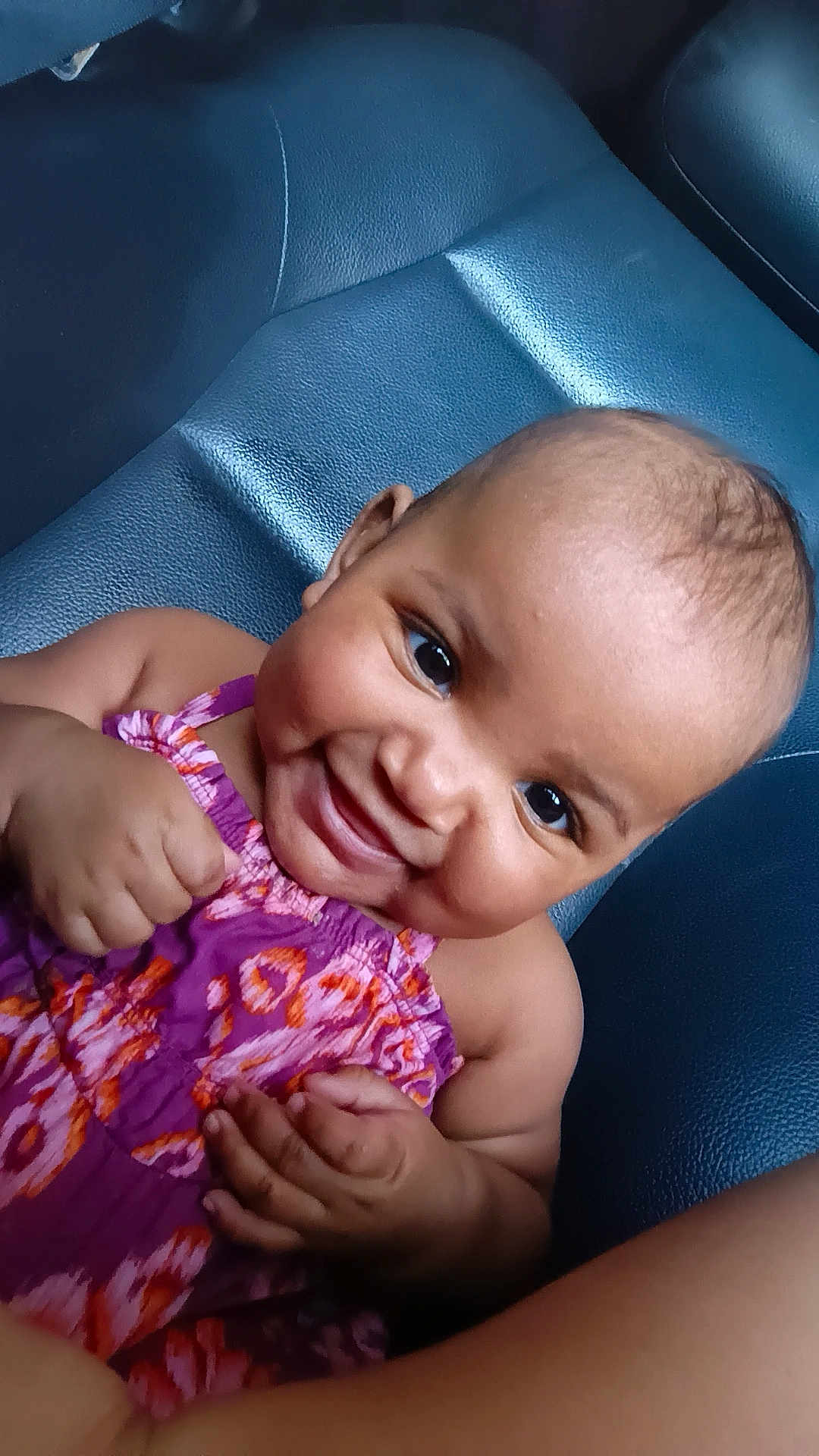 Mileyah joined the competition — help win amazing prizes! baby, child, smiling, face, happy, purple_dress, patterned_clothing, skin, arm, hand, seat, leather, closeup, portrait, infant, cute, young_child, person, indoors, sitting