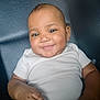 Mileyah joined the competition — help win amazing prizes! baby, child, smiling, face, hand, white_shirt, dark_background, sitting, infant, cute, portrait, skin, arm, clothing, person, happy, young_child, indoors, closeup, comfortable