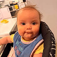 Elara is registered to the contest to win money with this photo: baby, child, bib, high_chair, messy, food, face, hair, kitchen, indoor, person, wide_eyes, curious, cute, infant, smudge, yellow_clothing, pink_trim, seated, closeup