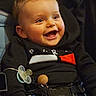 accessory, baby, belt, black_clothing, blond_hair, blue_eyes, candid, cheeks, child, hand, happy, harness, hoodie, indoors, infant, pacifier, portrait, seat, smiling, teeth