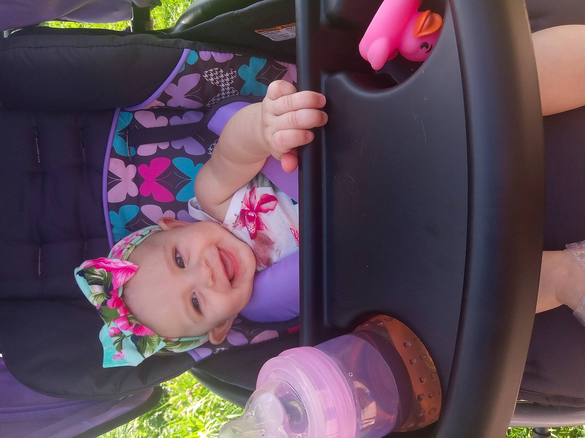 Luciana is registered to the contest to win money with this photo: auto_part, baby, baby_carriage, baby_toddler_clothing, car_seat, child, fun, grass, happy, headwear, joy, leisure, motor_vehicle, person, pink, plant, purple, seat_belt, smile, steering_wheel