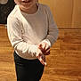 black_pants, casual_clothing, child, cute, flooring, footwear, hands, happy, home, indoor, person, portrait, short_hair, smiling, standing, toddler, white_shirt, white_sneakers, wooden_floor, young_child