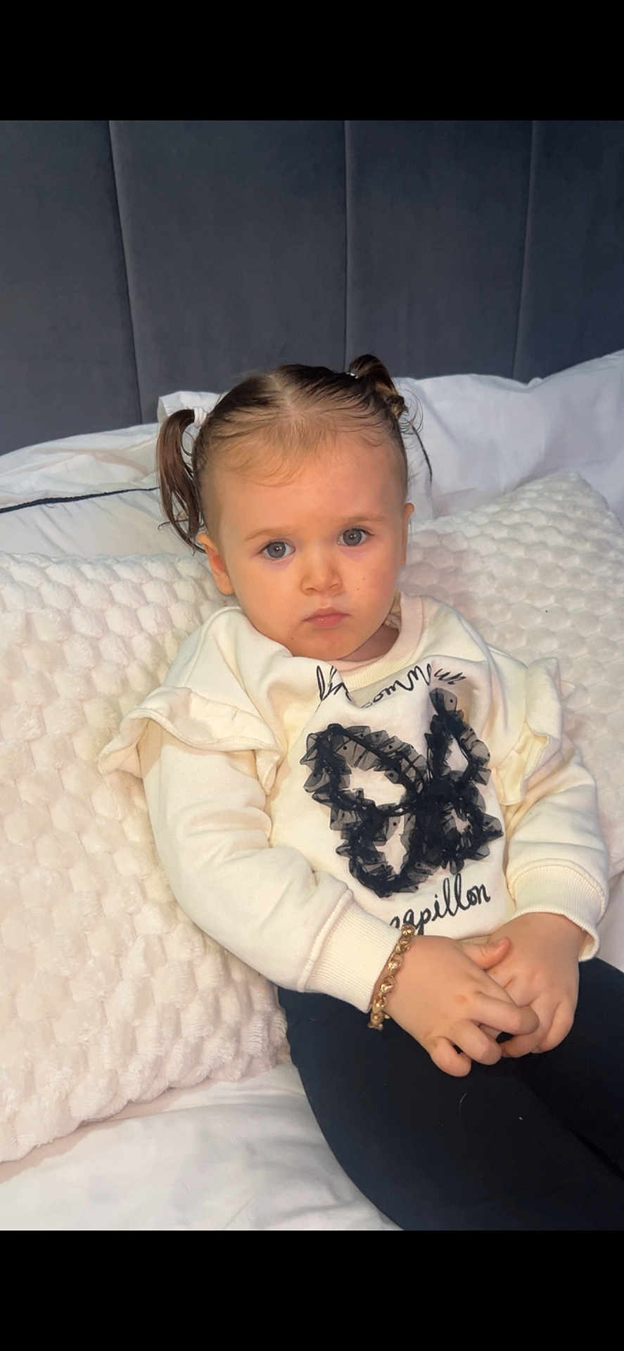 Zylah is registered to the contest to win money with this photo: toddler, child, pigtails, bracelet, sweater, butterfly, bed, pillow, white, cute, portrait, indoors, serious, hands, sitting, young, person, fashion, cozy, casual