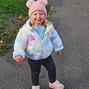 Lottie is registered to the contest to win money with this photo: toddler, child, smiling, outdoor, path, pavement, grass, jacket, hat, pink, shoes, happy, winter_clothing, walking, cute, person, nature, daylight, young_child, casual