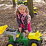 Lilly joined the competition — help win amazing prizes! child, girl, toy_tractor, outdoor, forest, trees, leaves, play, pigtails, headband, pink_clothing, smile, happy, nature, daylight, ground, yellow, green, playground, fun