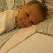 Wilfried a rejoint le concours — aidez-le/la à gagner de superbes lots ! child, smiling, bed, pillow, face, resting, pattern, fabric, cozy, young, indoor, portrait, cute, sleepy, head, clothing, comfort, relaxation, person, closeup
