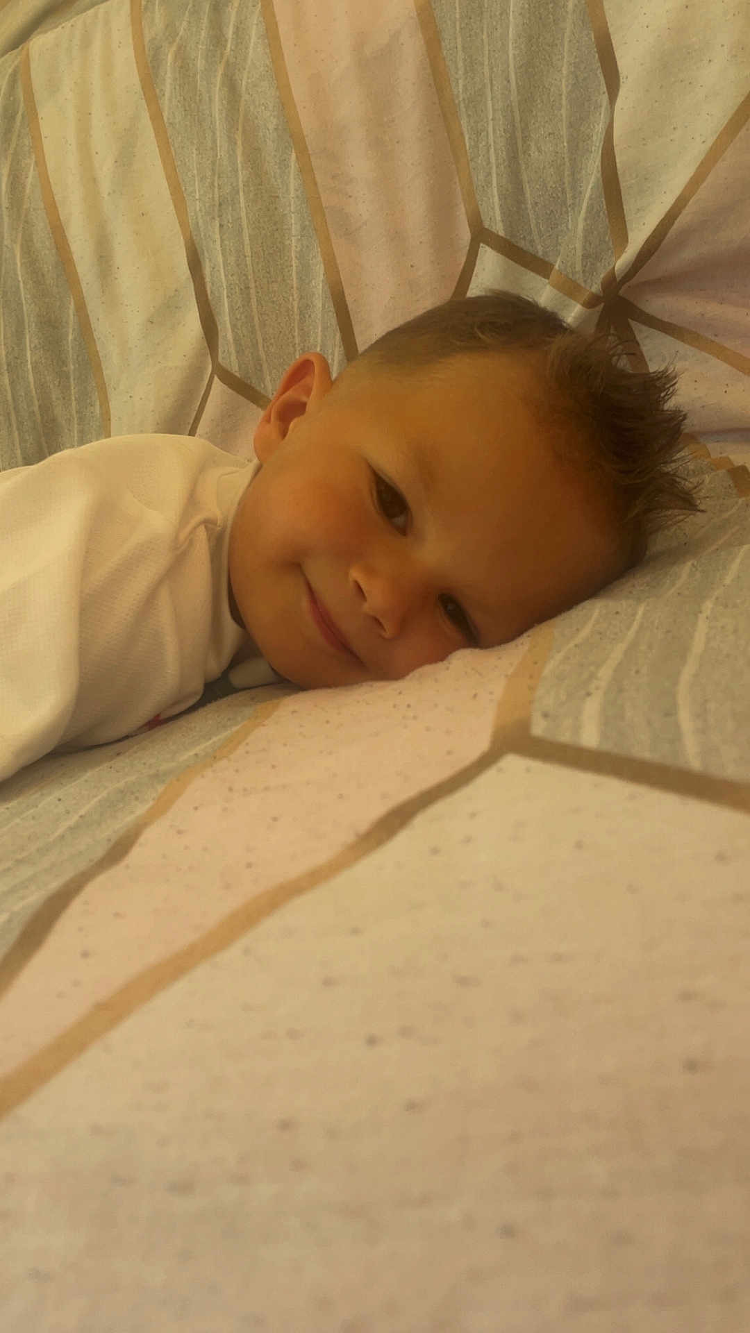 Wilfried a rejoint le concours — aidez-le/la à gagner de superbes lots ! child, smiling, bed, pillow, face, resting, pattern, fabric, cozy, young, indoor, portrait, cute, sleepy, head, clothing, comfort, relaxation, person, closeup