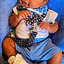 Hayden joined the competition — help win amazing prizes! baby, infant, child, blue_shorts, white_shoes, bib, blanket, pacifier_clip, curly_hair, cute, soft_texture, lying_down, casual_clothing, indoor, relaxed, close_up, person, smiling, skin, footwear