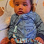 baby, infant, onesie, blue_clothing, pacifier, blanket, indoor, cute, child, face, hand, patterned_clothing, seated, comfort, soft_texture, curly_hair, expression, portrait, young_child, colorful