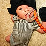 baby, baby_clip, beanie, child, close_up, cozy, eyes, face, fashion, fluffy_rug, hat, indoor, infant, lying_down, orange_beads, pacifier, portrait, romper, smiling, striped_clothing
