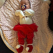 Chloee joined the competition — help win amazing prizes! baby, infant, pacifier, blanket, red_clothing, tutu, booties, sleepy, indoors, cute, child, soft_texture, person, lying_down, holiday_theme, cozy, warm, newborn, comfort, resting