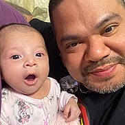 Harmony joined the competition — help win amazing prizes! baby, man, adult, child, face, smile, surprised, expression, portrait, indoor, clothing, beard, short_hair, person, holding, blanket, pink, purple, black_shirt, closeup