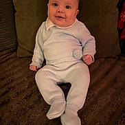 Reggie joined the competition — help win amazing prizes! baby, child, knitwear, blue_clothing, smile, happy, indoors, blanket, pillow, cozy, sitting, cute, portrait, infant, warm, face, person, soft_texture, home, comfort