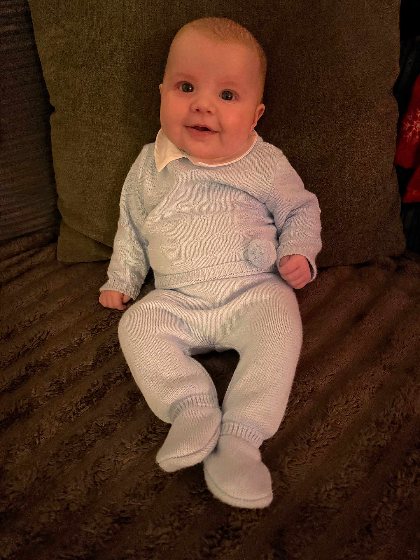 Reggie joined the competition — help win amazing prizes! baby, child, knitwear, blue_clothing, smile, happy, indoors, blanket, pillow, cozy, sitting, cute, portrait, infant, warm, face, person, soft_texture, home, comfort