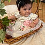 baby, child, wicker_basket, white_dress, pink_flowers, headband, flower, leaf, greenery, indoor, floor, wooden_floor, cute, smile, portrait, infant, adorable, sitting, bracelet, decorative