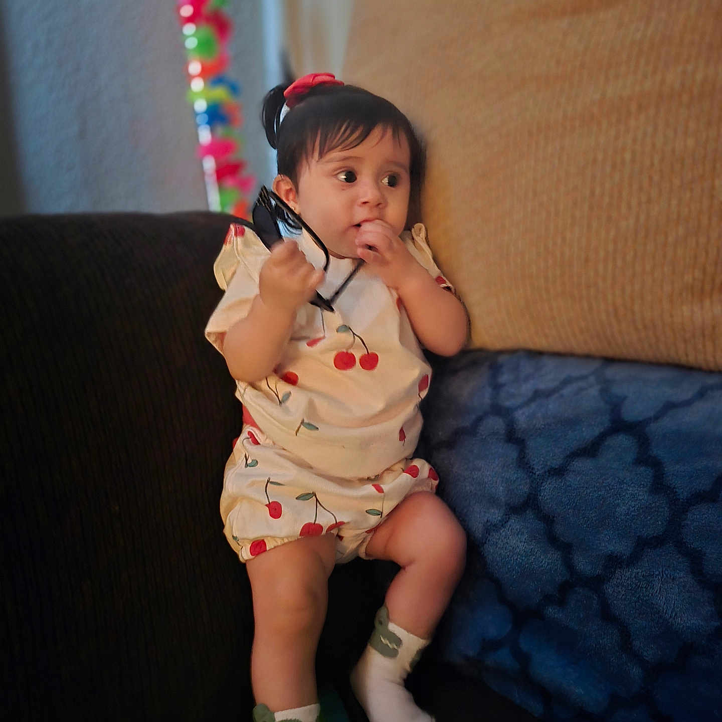 Mayra joined the competition — help win amazing prizes! blurred_background, cherry, child, clothing, colorful, cozy, curious, cushion, expression, face, hair, home, indoor, pattern, person, socks, sofa, sunglasses, toddler, toy