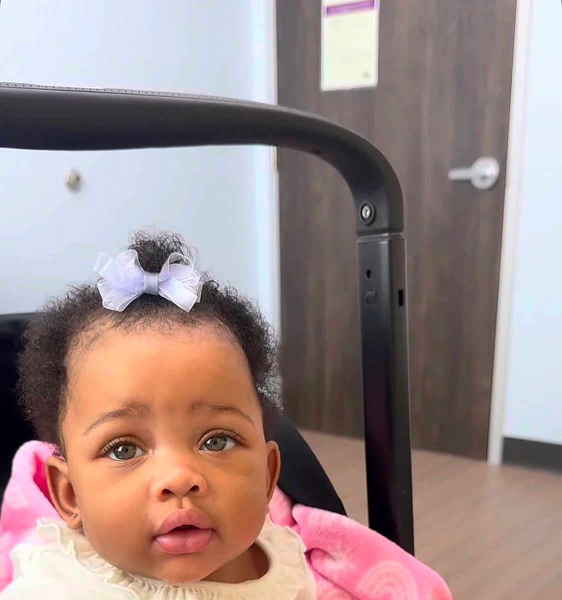 Kenzlii joined the competition — help win amazing prizes! baby, child, infant, bow, curly_hair, stroller, pink_blanket, indoor, door, wooden_door, face, portrait, cute, adorable, expression, clothing, person, head, eyes, mouth