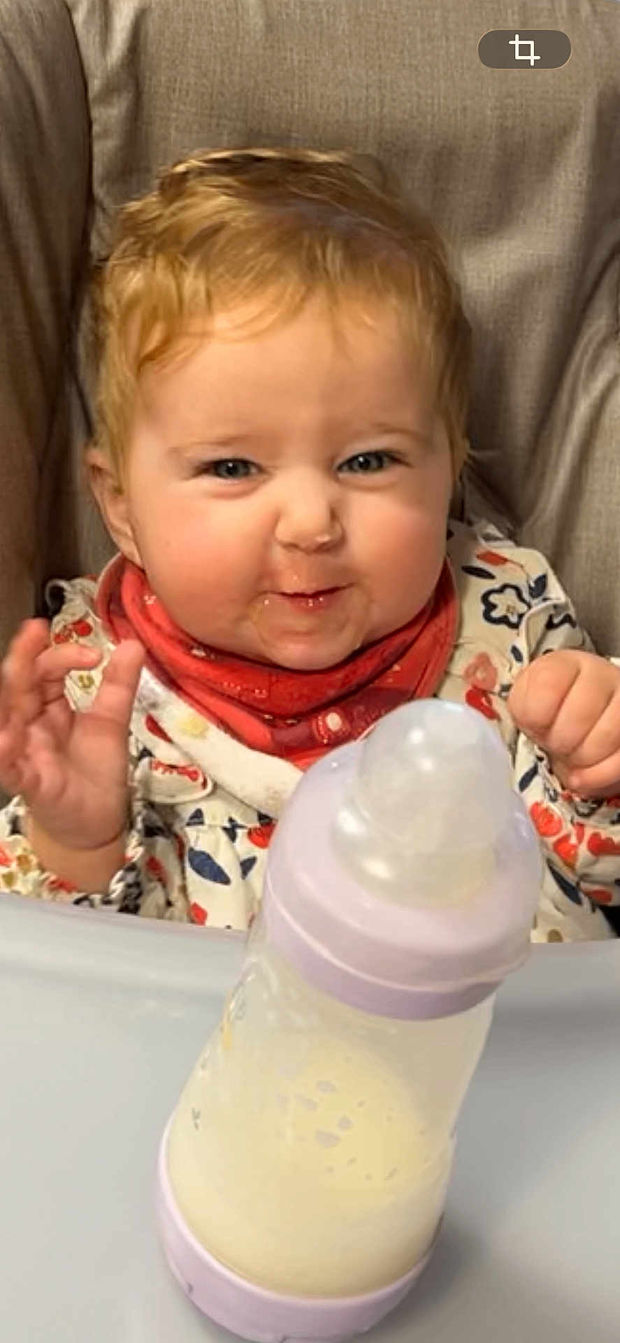 Lou participe au concours pour gagner de l'argent avec cette photo : baby, infant, high_chair, bottle, milk, bib, curly_hair, blonde, cute, smile, face, hand, funny_expression, feeding, table, clothing, indoor, child, person, closeup