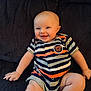 baby, baby_boy, baby_girl, child, couch, cute, expression, face, hand, happy, head, indoor, infant, legs, onesie, portrait, sitting, skin, smiling, striped_clothing