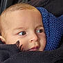 baby, infant, face, eyes, close_up, knit_scarf, blanket, car_interior, car_window, seat, portrait, brown_eyes, head, cheek, cozy, wrapped, clothing, looking_away, outdoor_background, red_building