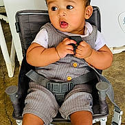 Daniel is registered to the contest to win money with this photo: baby, child, face, expression, curious, chair, seatbelt, gray_outfit, striped_socks, hands, legs, indoor, floor, concrete, casual_clothing, cute, portrait, sitting, infant, young_child
