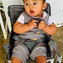 baby, child, face, expression, curious, chair, seatbelt, gray_outfit, striped_socks, hands, legs, indoor, floor, concrete, casual_clothing, cute, portrait, sitting, infant, young_child