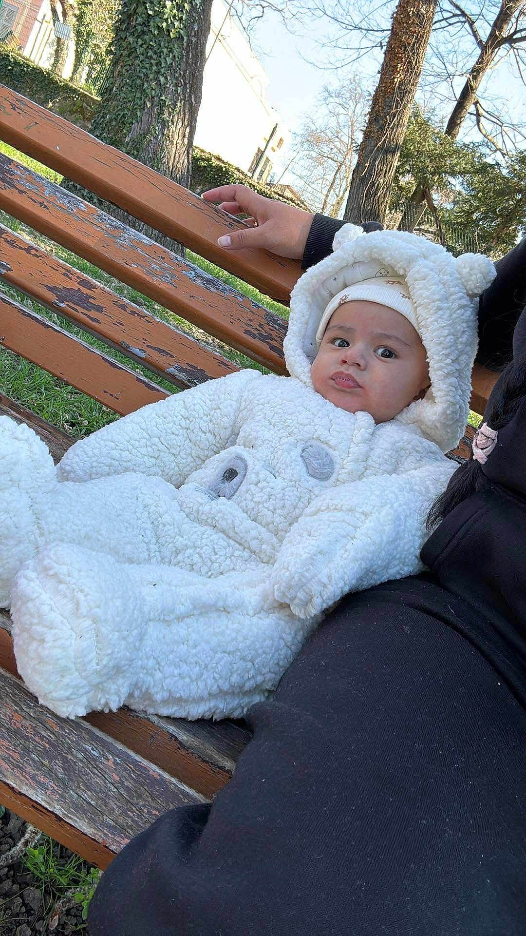 Aylan a rejoint le concours — aidez-le/la à gagner de superbes lots ! baby, infant, child, park, bench, wooden_bench, coat, hood, hat, fuzzy_suit, plush, outdoors, trees, grass, hand, person, portrait, sitting, cute, winter_clothing
