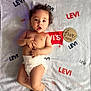 baby, infant, diaper, curly_hair, blanket, levi's, wooden_sign, five_months, milestone, cute, lying_down, soft_texture, skin, portrait, child, young, happy, indoors, closeup, smiling