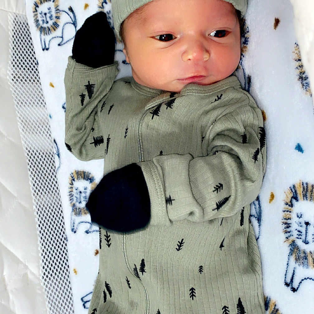 Colton is registered to the contest to win money with this photo: baby, beanie, bed, blanket, bonnet, cap, clothing, cradle, crib, face, furniture, glove, hat, head, infantbed, knitwear, newborn, person, photography, portrait