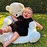 Maëlle a rejoint le concours — aidez-le/la à gagner de superbes lots ! baby, teddy_bear, outdoor, grass, smiling, child, plush, hedge, greenery, sunlight, cute, playing, happy, black_clothing, feet, toy, nature, summer, infant, portrait