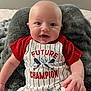 baby, infant, smiling, clothing, red_shirt, striped_outfit, blanket, indoor, portrait, happy, cute, child, baby_hand, sitting, face, person, soft_texture, comfort, young, casual