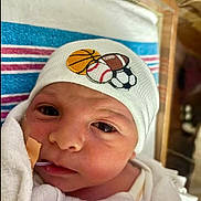 Thomas joined the competition — help win amazing prizes! newborn, baby, infant, hat, sports_balls, blanket, face, wrapped, medical_tube, bandage, cute, indoors, closeup, portrait, headwear, child, soft, expression, young, person