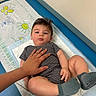 Thomas joined the competition — help win amazing prizes! baby, cartoon_prints, changing_pad, changing_table, child, curly_hair, expression, face, footwear, furniture, hand, indoor, infant, legs, lying_down, person, resting, skin, socks, striped_clothing