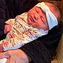 newborn, baby, infant, headband, floral_clothing, sleeping, person, hands, indoor, kitchen, wooden_cabinet, floor, cozy, closeup, portrait, cute, soft_lighting, toddler, child, family
