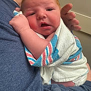 Kannan is registered to the contest to win money with this photo: adult_hand, baby, blanket, blue_shirt, caring, closeup, diaper, face, head, holding, hospital, indoor, infant, newborn, newborn_care, person, portrait, skin, soft_light, striped_blanket