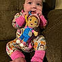 baby, child, pajamas, plush_toy, couch, foot, hand, smile, face, sitting, indoors, toy, colorful, cute, comfort, happy, infant, person, soft_lighting, closeup