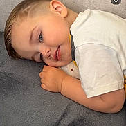 Lyam a rejoint le concours — aidez-le/la à gagner de superbes lots ! child, toddler, sleeping, lying_down, face, cheek, hand, white_shirt, short_hair, portrait, closeup, indoors, blanket, soft_texture, cute, resting, smile, eyelashes, pillow_like, relaxed