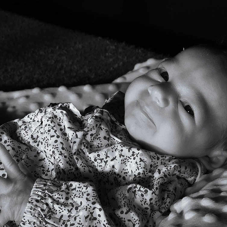 Mia participe au concours pour gagner de l'argent avec cette photo : baby, bedding, black_and_white, blanket, cheek, cozy, cute, eyes, face, hand, head, infant, lying_down, monochrome, newborn, newborn_clothes, patterned_clothing, portrait, smile, soft_texture