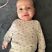 Mia a rejoint le concours — aidez-le/la à gagner de superbes lots ! baby, infant, onesie, floral_pattern, blanket, smiling, wide_eyes, face, head, hand, lying_down, soft_texture, cozy, adorable, newborn, portrait, clothing, happy, nursery, fist