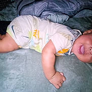 Kayleb is registered to the contest to win money with this photo: baby, infant, smiling, tongue_out, lying_down, blanket, clothing, cute, child, face, hand, soft_texture, indoors, happy, playful, young_child, portrait, skin, person, toddler