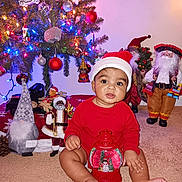 Kayleb joined the competition — help win amazing prizes! baby, carpet, celebration, child, christmas, cute, decorations, dolls, festive, holiday, holiday_spirit, indoor, lights, ornaments, red_clothing, santa_hat, smiling, snow_globe, toys, winter