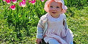 Frankie is registered to the contest to win money with this photo: baby, child, tulips, flowers, grass, sun_hat, pink_dress, smiling, outdoor, spring, nature, greenery, garden, sitting, cute, sunny, daylight, happy, person, portrait