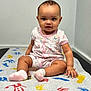Belen is registered to the contest to win money with this photo: baby, child, infant, sitting, onesie, pink, socks, handprints, footprints, colorful, table, floor, indoor, curious, cute, portrait, skin, face, person, young