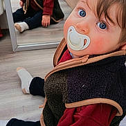 Maël a rejoint le concours — aidez-le/la à gagner de superbes lots ! baby, pacifier, blue_eyes, reflection, mirror, fleece_vest, red_sweater, sitting, wooden_floor, indoor, child, person, hand, footwear, casual_clothing, cozy, home, cute, portrait, photography