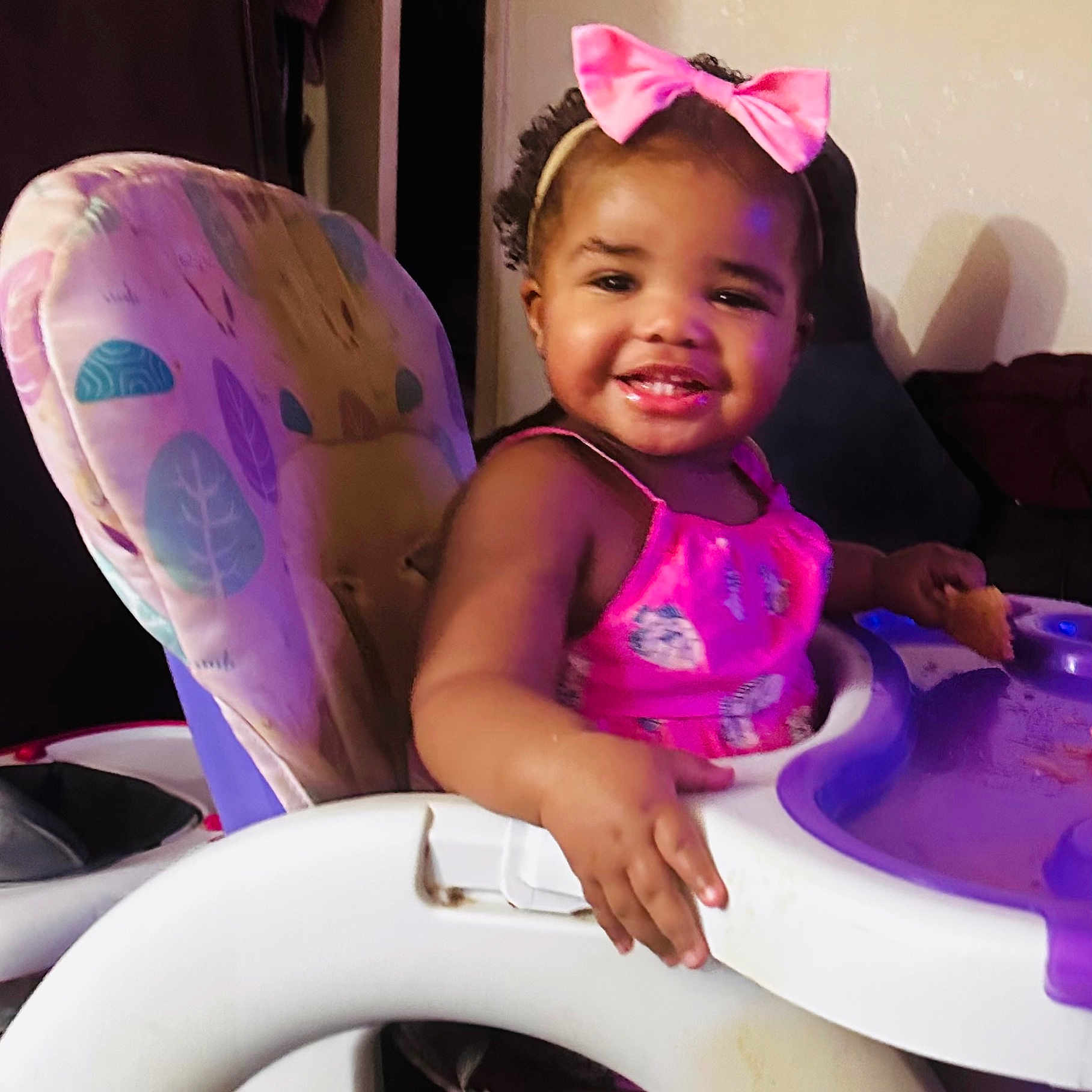 Jurnee joined the competition — help win amazing prizes! baby, bow, child, curly_hair, cute, feeding, food, furniture, happy, high_chair, home, indoor, person, pink_dress, playful, portrait, seat, smiling, toddler, young_child